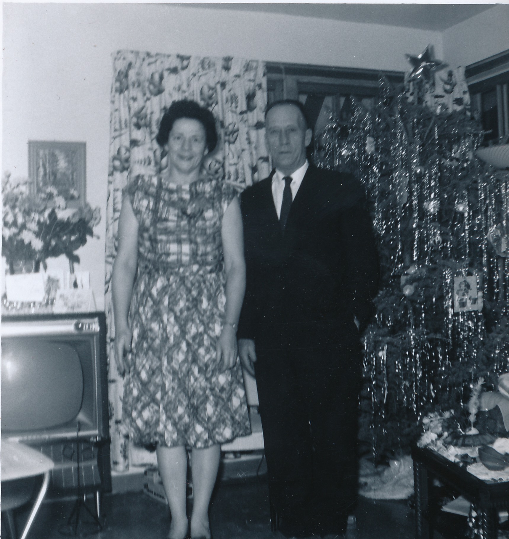 Black-and-white photograph of Grace Davis Simpson and Lowell Simpson standing indoors beside a Christmas tree.