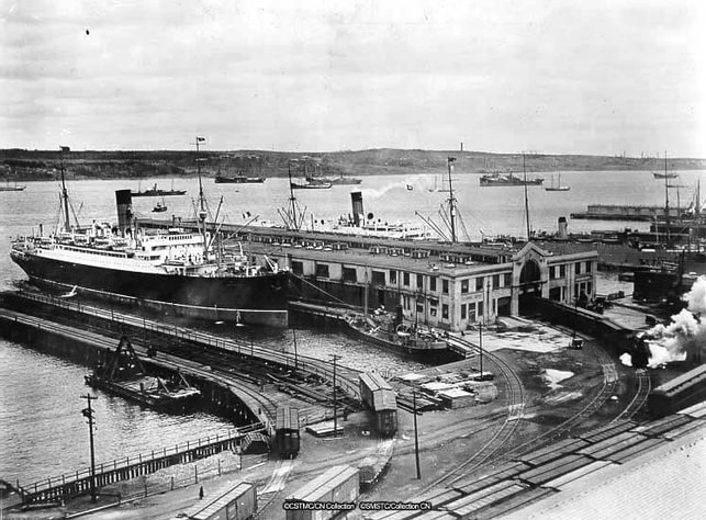 Ships, immigration buildings, and railway tracks at Halifax harbour.